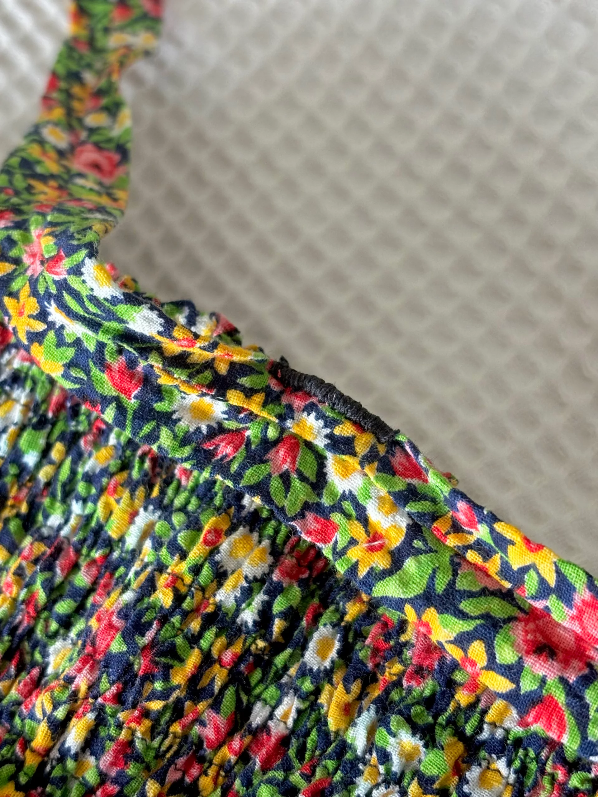 A close-up view of the tight zigzag stitch used to secure the off-shoulder sleeve straps to the dress.