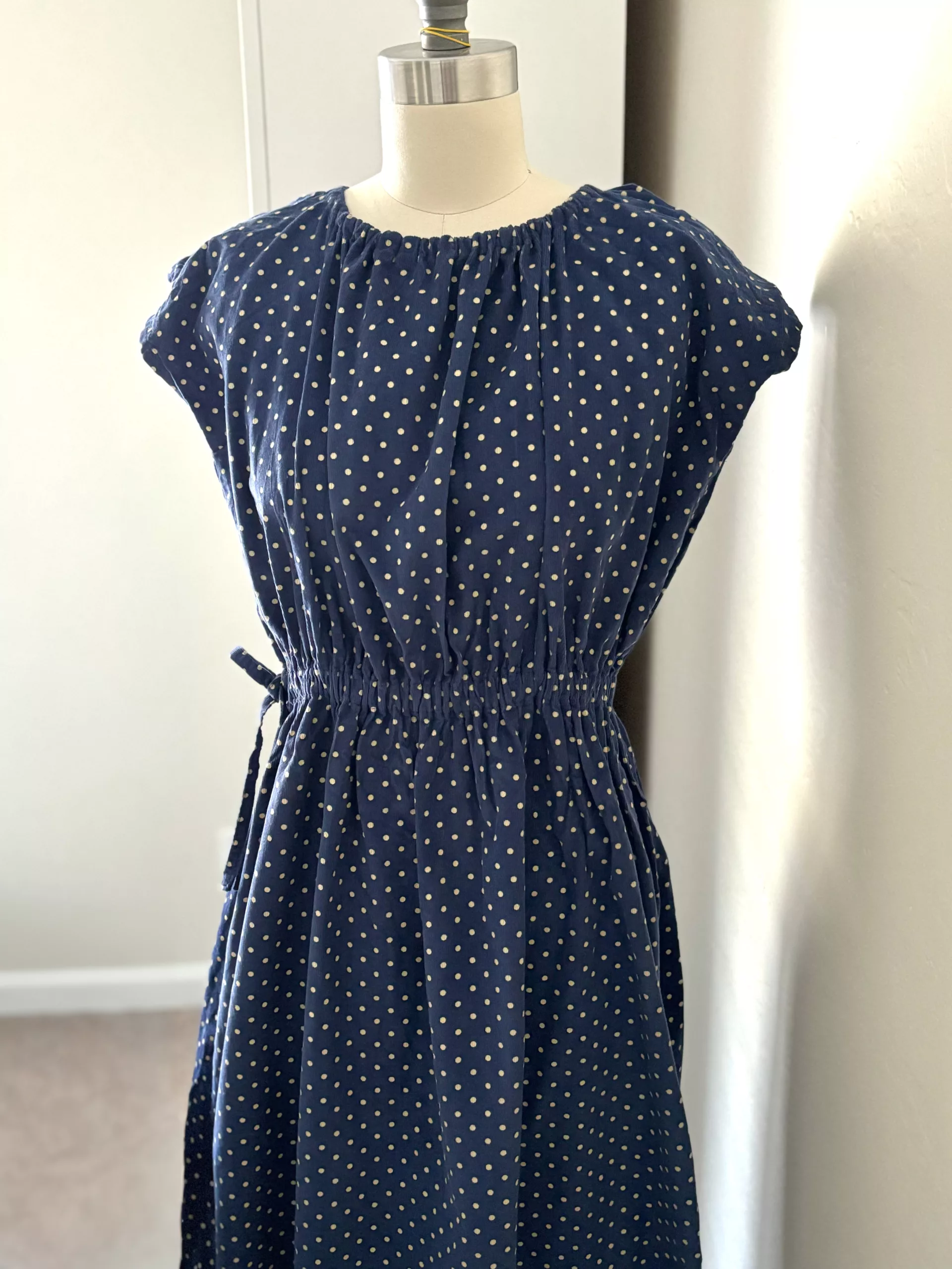 A full view of the polka dot blue waist ribbon dress.