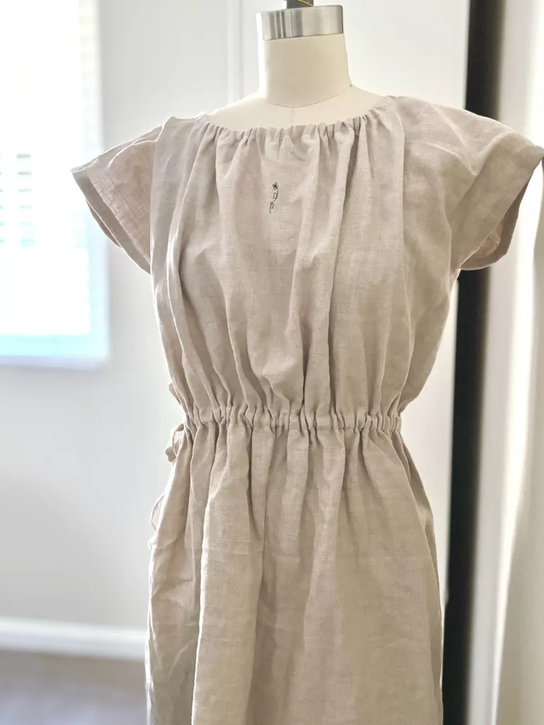 A full view of the beige linen waist ribbon dress.