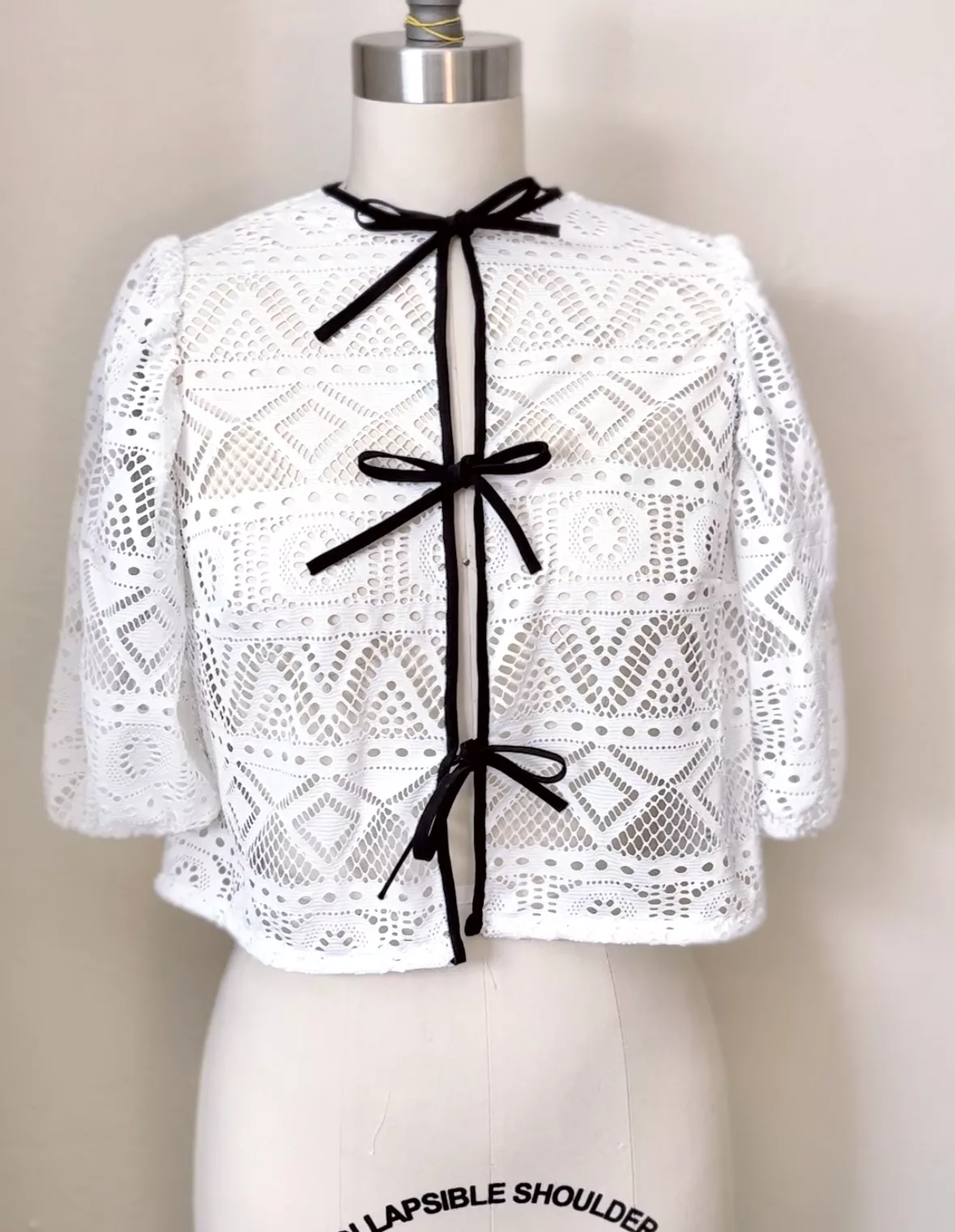 The finished open-knit white cardigan on a dress form